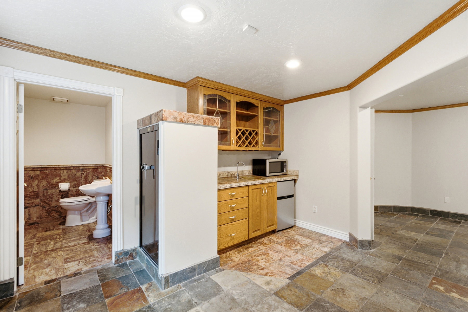 Entertainment area featuring a wet bar with wood cabinetry, a built-in wine rack, and a stone-look countertop