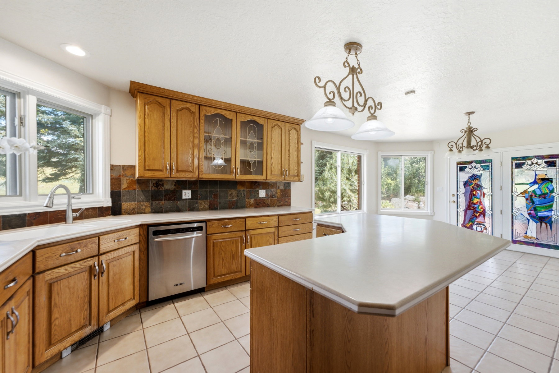 Kitchen featuring light wood cabinetry, a central island with a solid surface countertop, and tile flooring