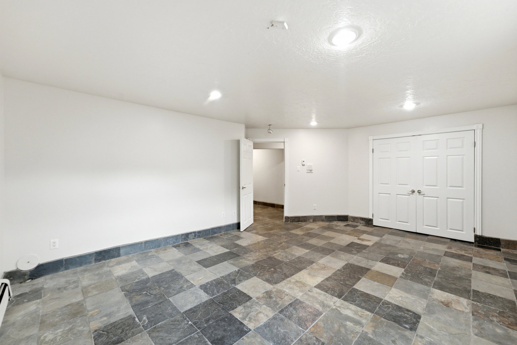 Spacious room featuring multi-toned slate tile flooring, white walls, and a recessed lighting system