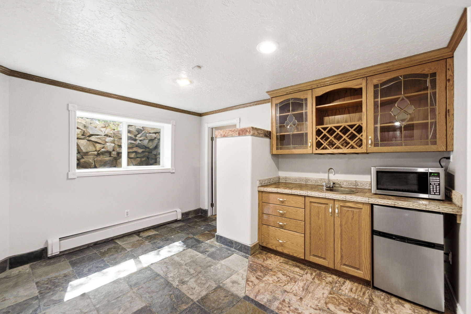Wet bar featuring wood cabinetry, granite-style countertops, stainless steel sink, and built-in wine rack