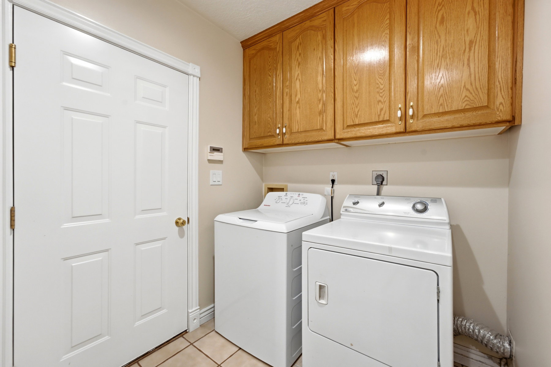 Dedicated utility space featuring light wood-finish cabinetry