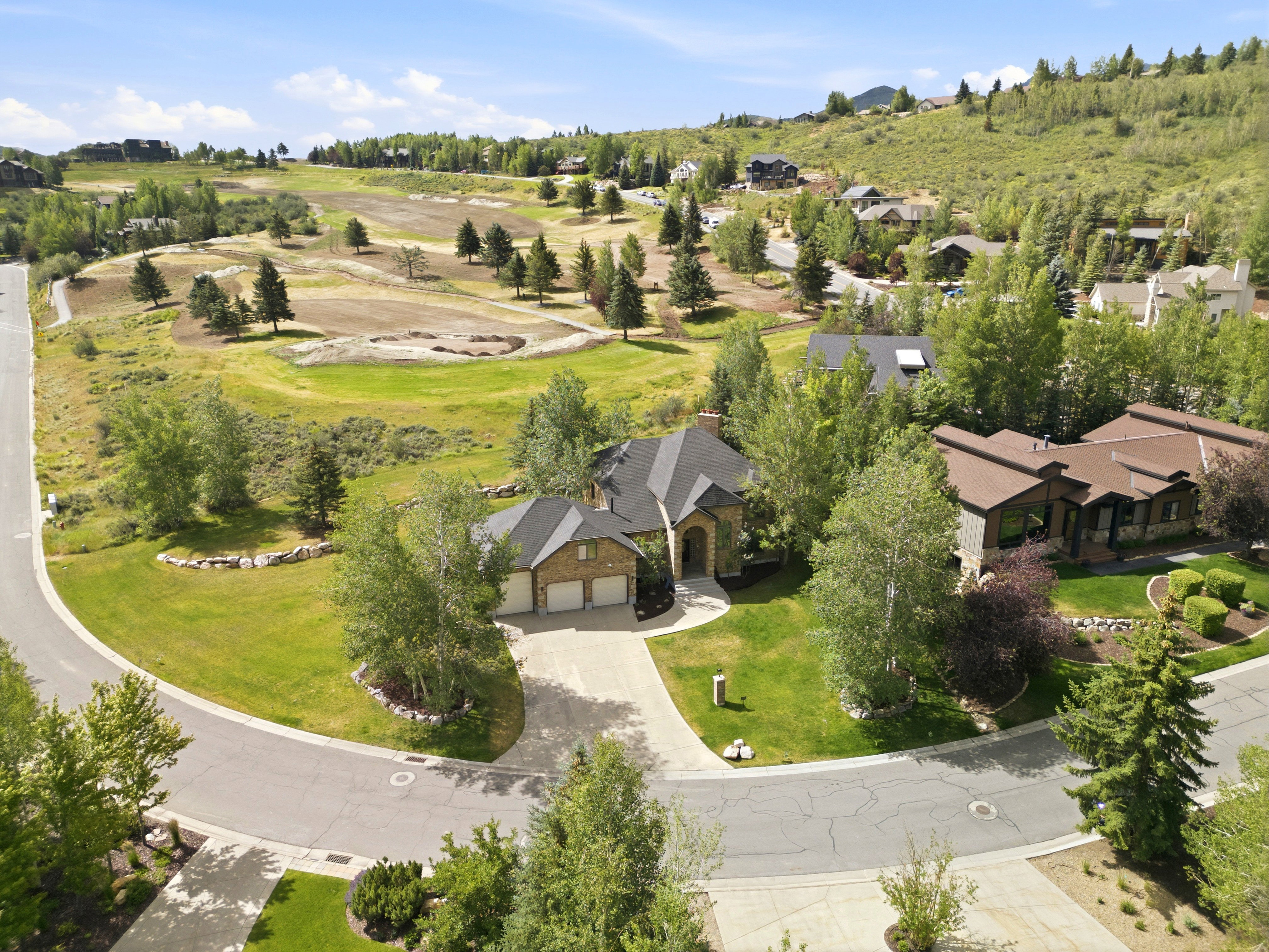Stone and brick exterior residence featuring a multi-car garage, established landscaping, and a paved driveway within a cul-de-sac