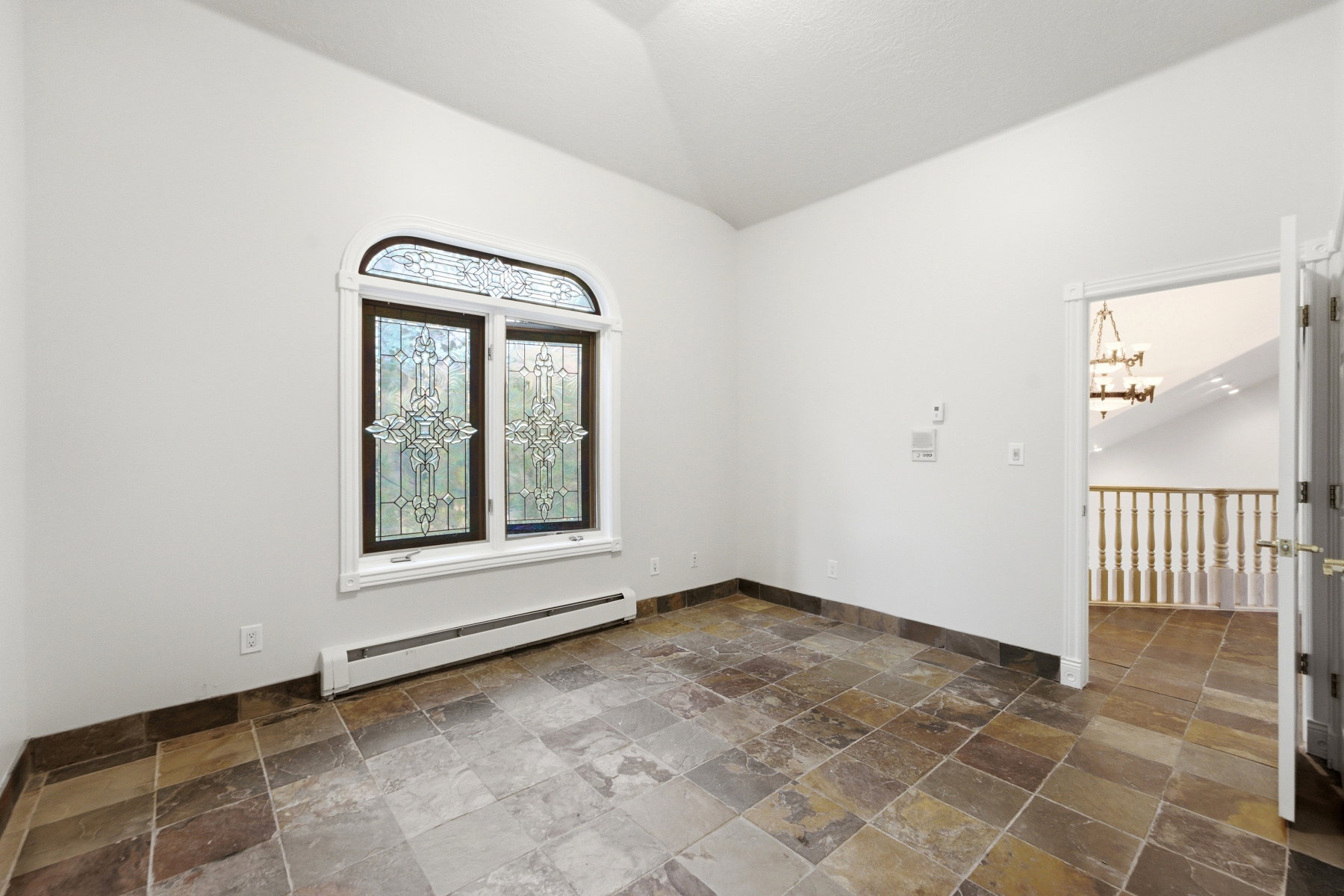 Room featuring a vaulted ceiling and multi-toned slate tile flooring