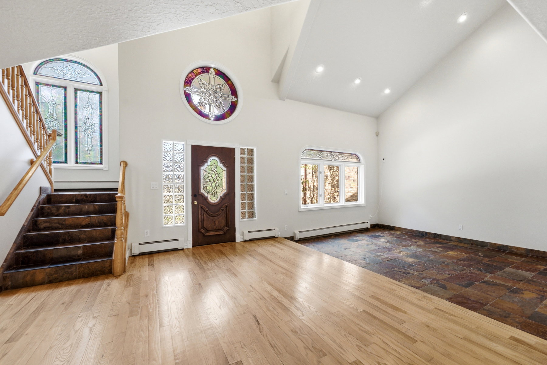 Grand entry foyer featuring a vaulted ceiling and a mix of hardwood and stone-finish flooring