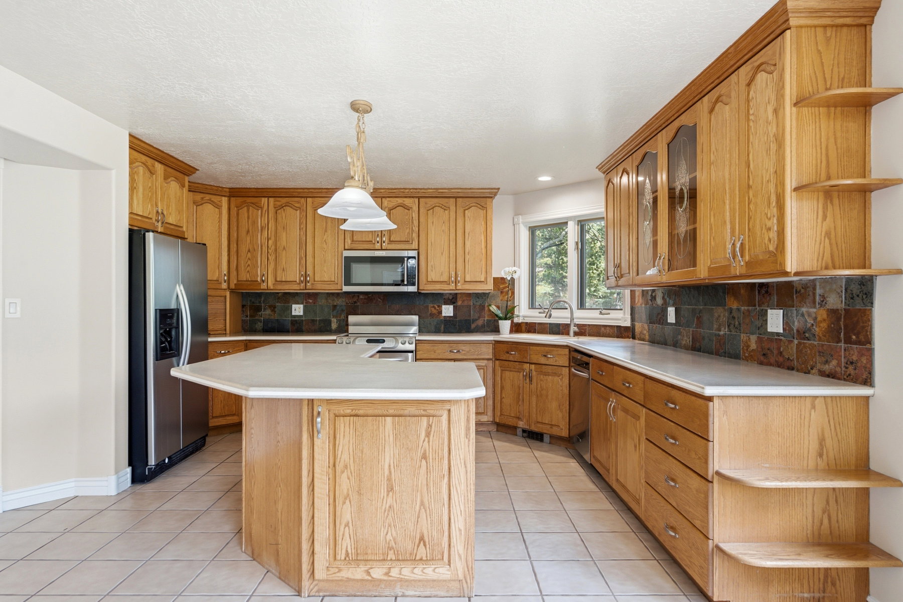 Kitchen featuring extensive wood cabinetry, tile flooring, and light-toned countertops