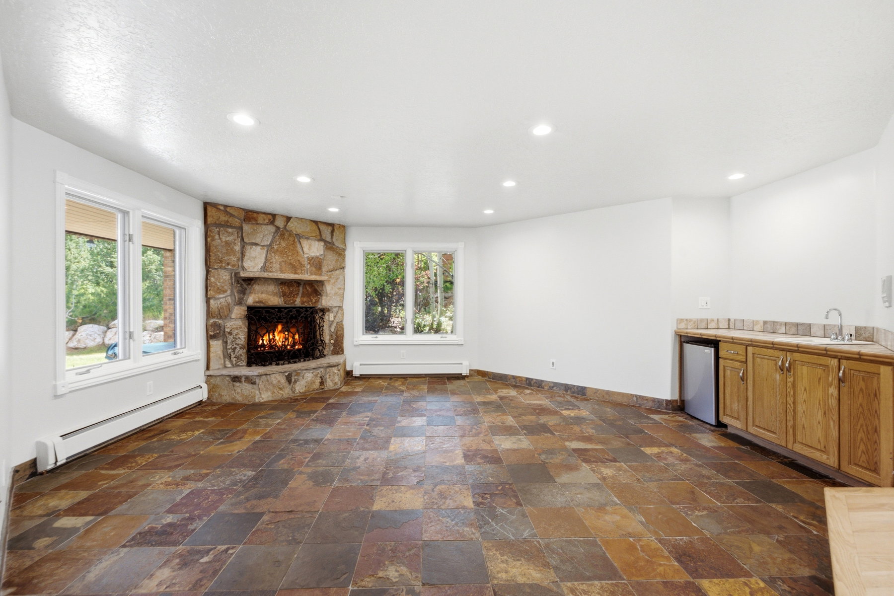 Corner stone fireplace with hearth, complemented by multi-toned slate tile flooring