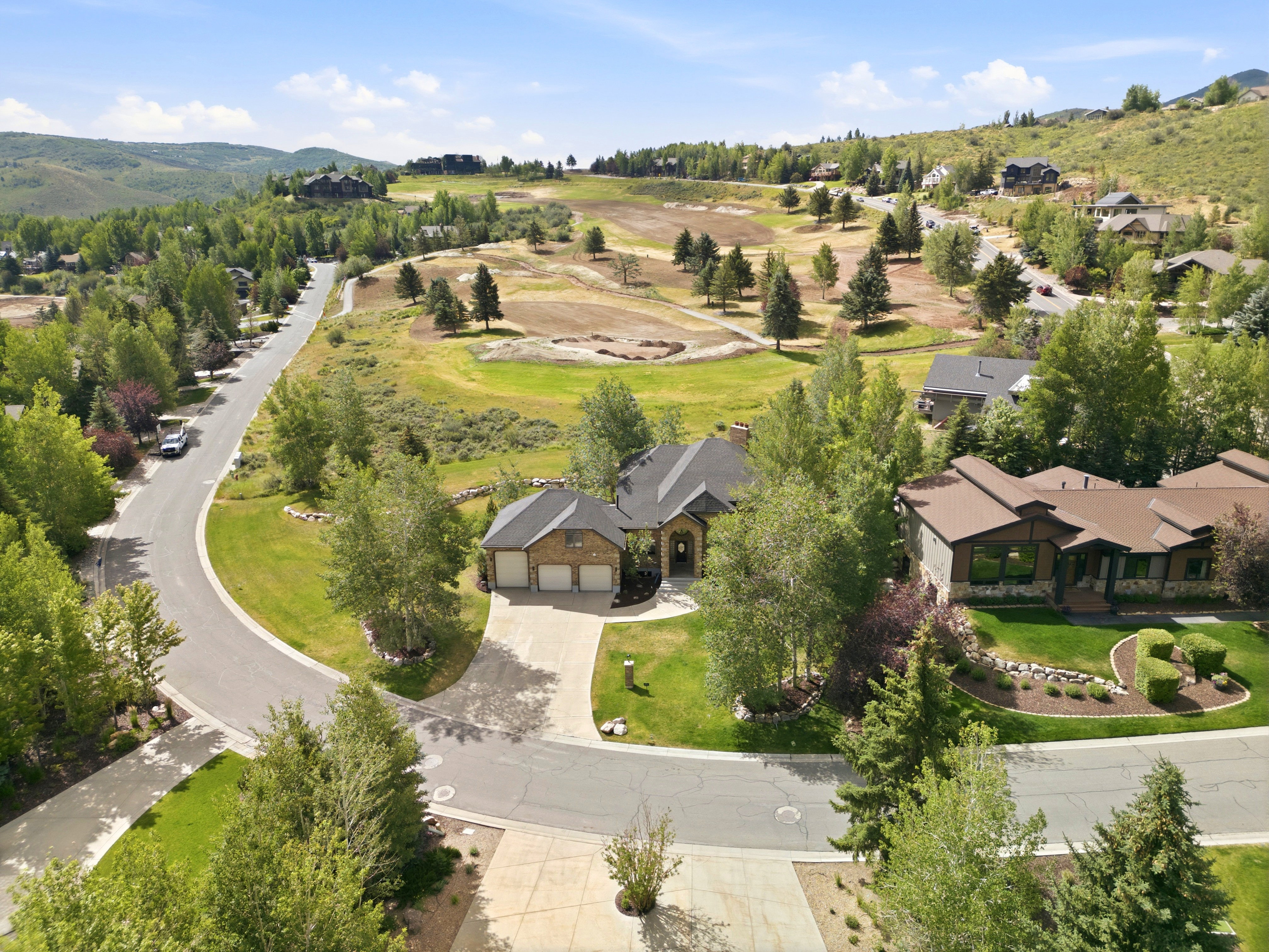 Expansive property on a curved street, featuring a paved driveway, attached two-car garage, and mature landscaping
