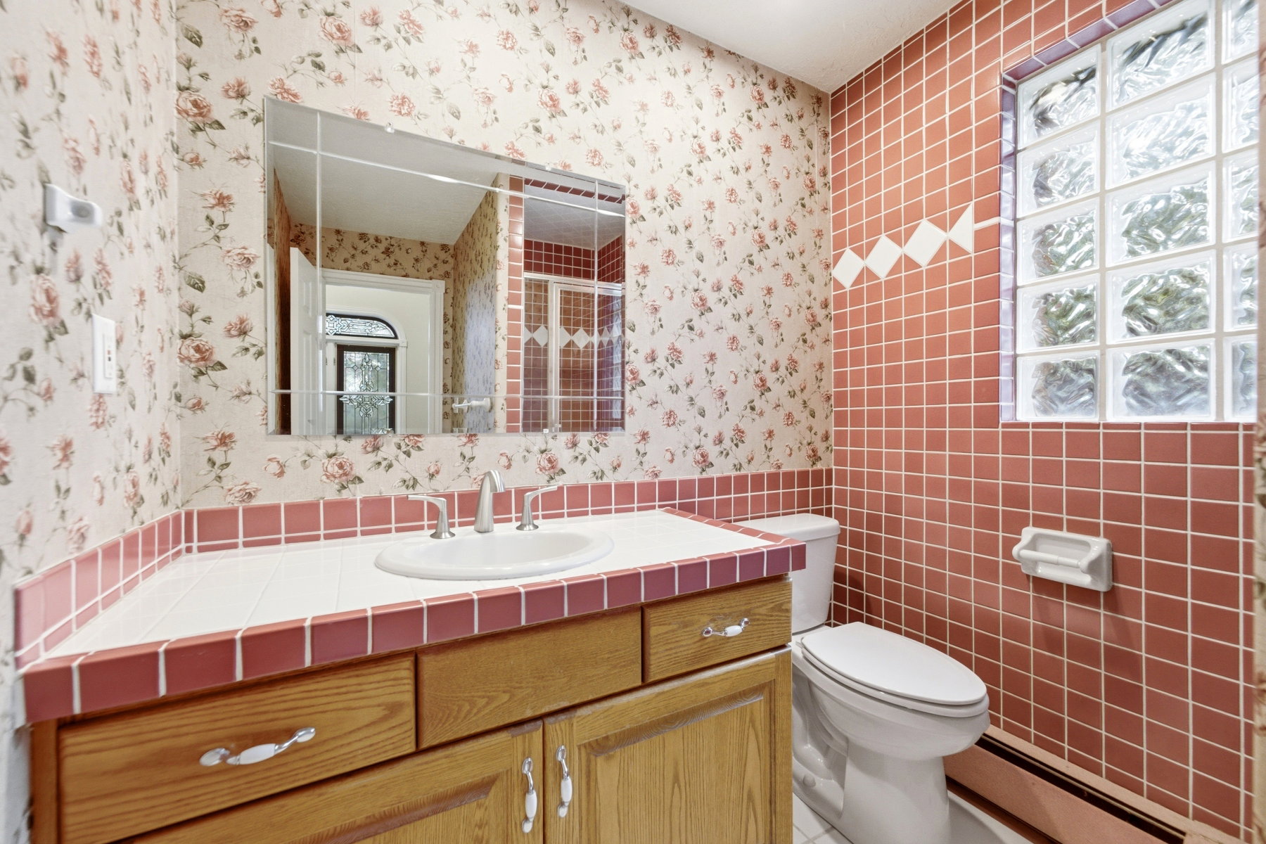 Bathroom featuring a wood vanity with a drop-in sink, a large wall mirror, and a toilet