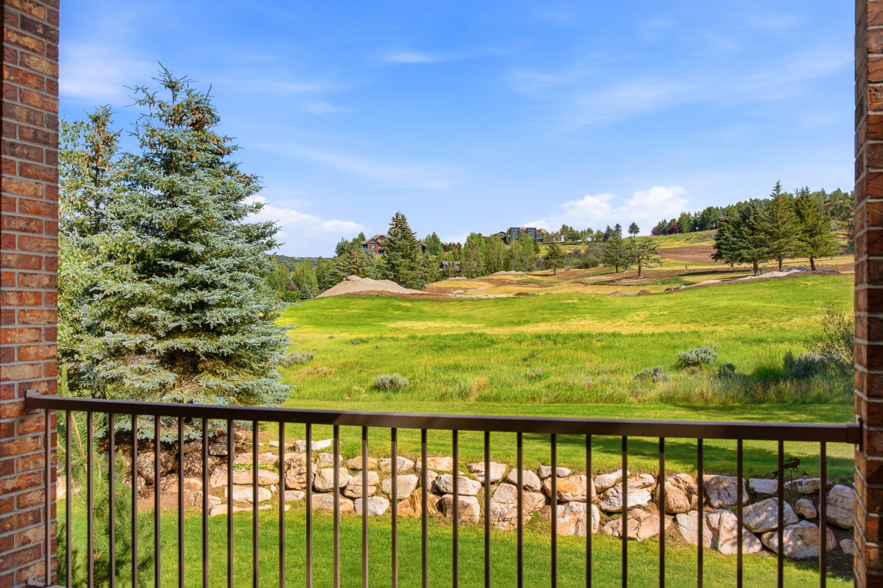 Balcony with a black metal railing overlooking expansive green landscapes