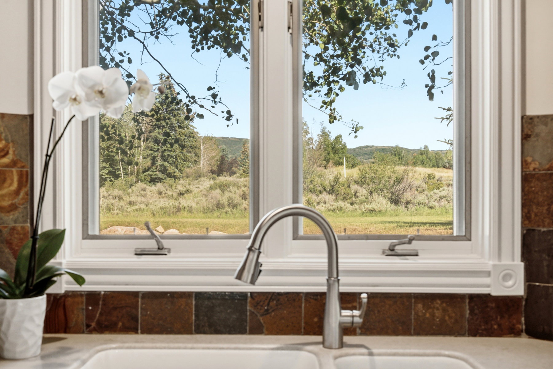 Double-hung window overlooking a natural landscape with distant hills