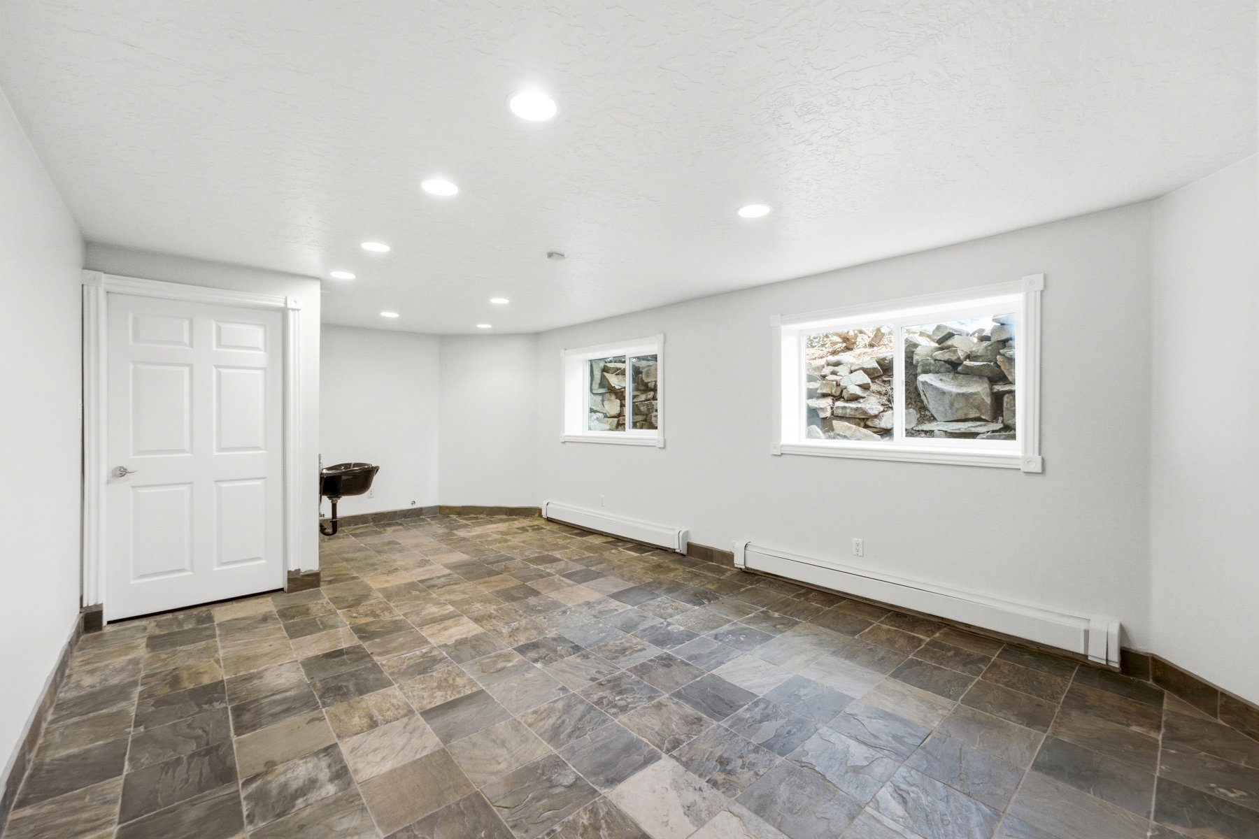 Spacious room featuring slate-style floor tiling, recessed lighting, and multiple windows