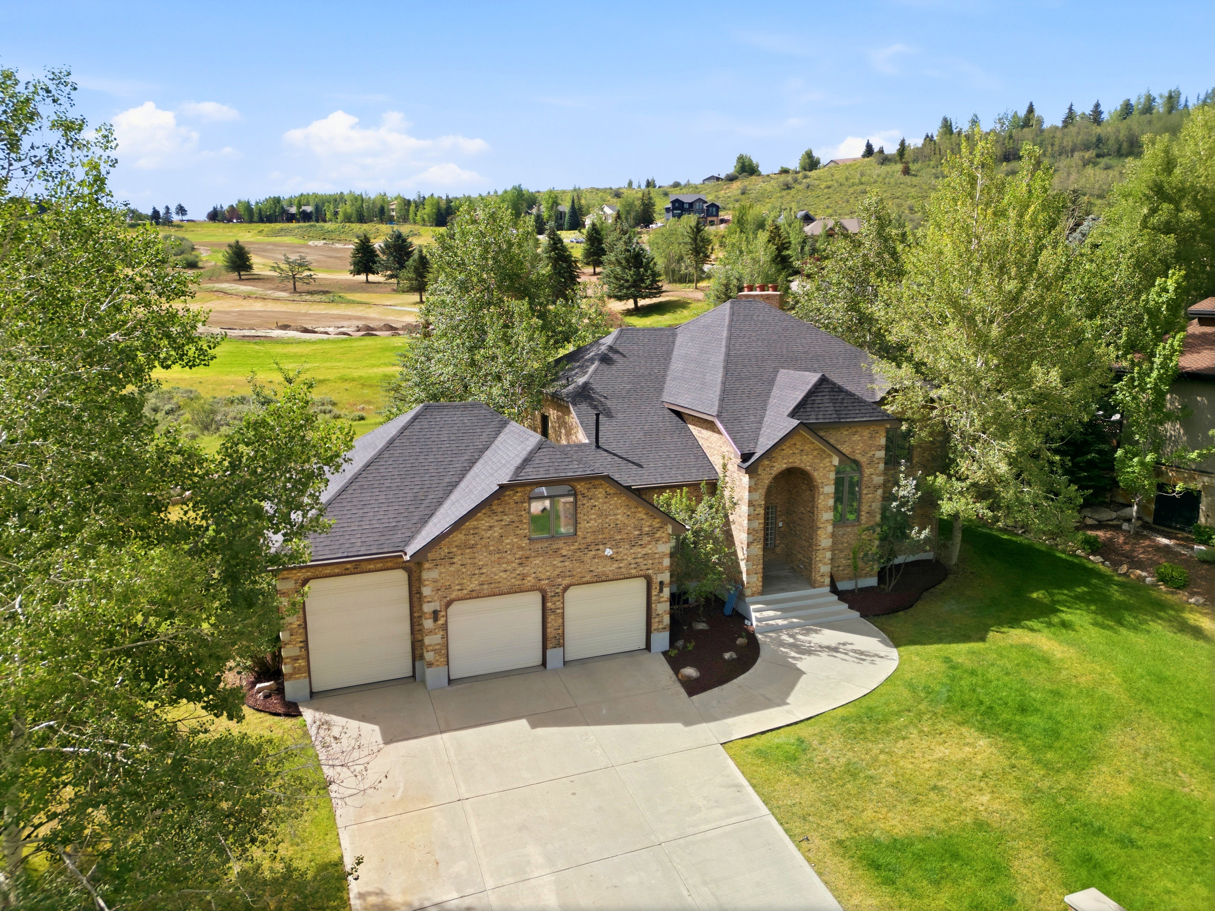 Stone-clad exterior featuring a prominent arched entry, a multi-car garage, and a dark shingle roof