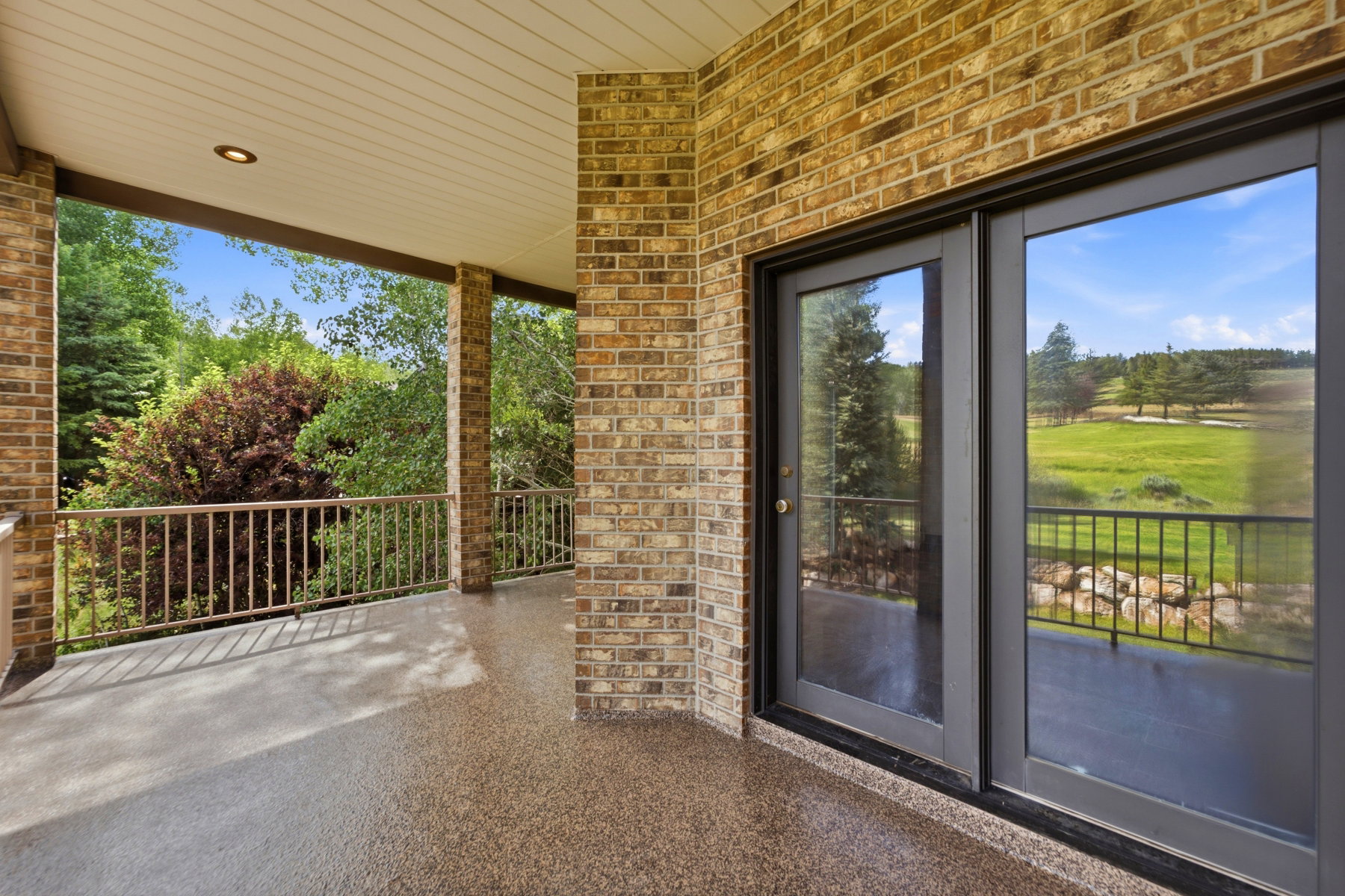 Covered outdoor patio featuring a brick exterior and a textured flooring surface