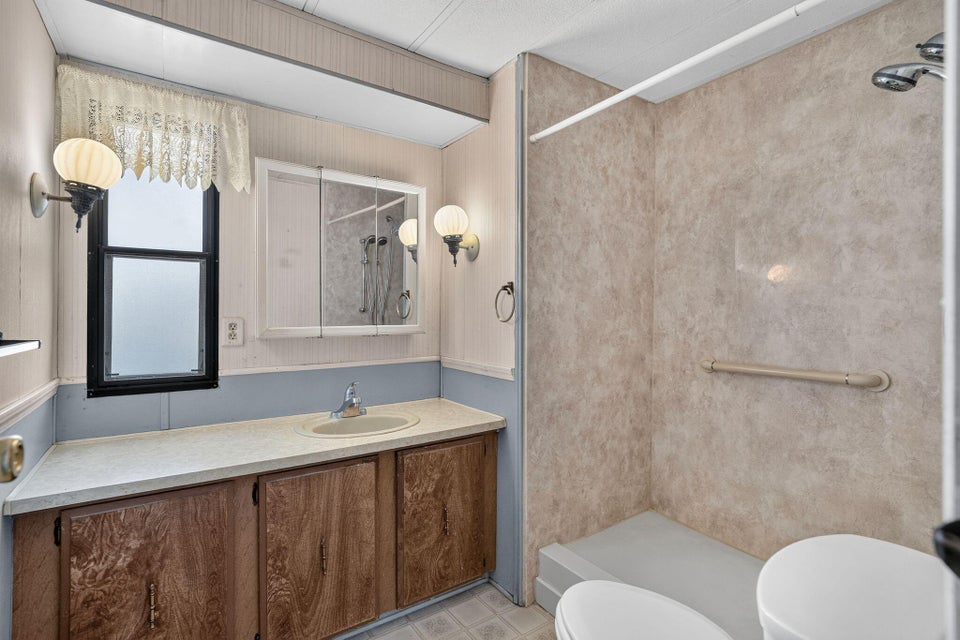 Bathroom featuring a walk-in shower with textured wall panels and a built-in grab bar