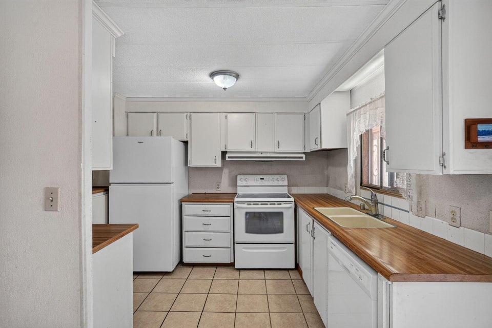 Kitchen featuring white cabinetry, wood-finish countertops, and a tile floor