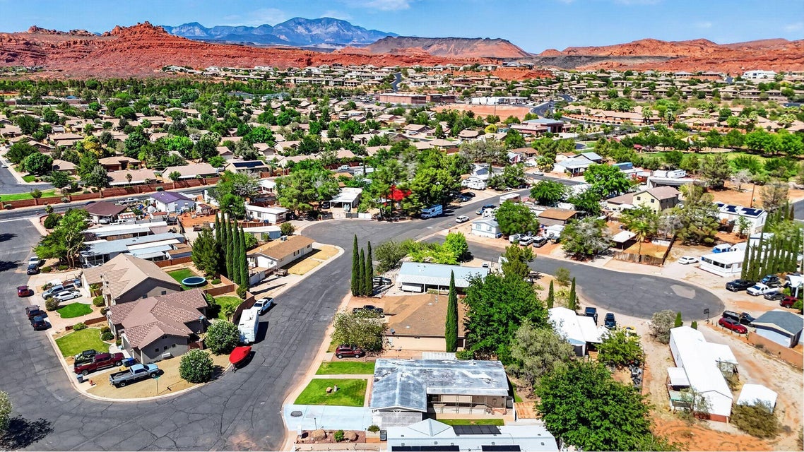 Residential neighborhood with mature trees, paved streets, and desert landscaping, set against a mountainous backdrop