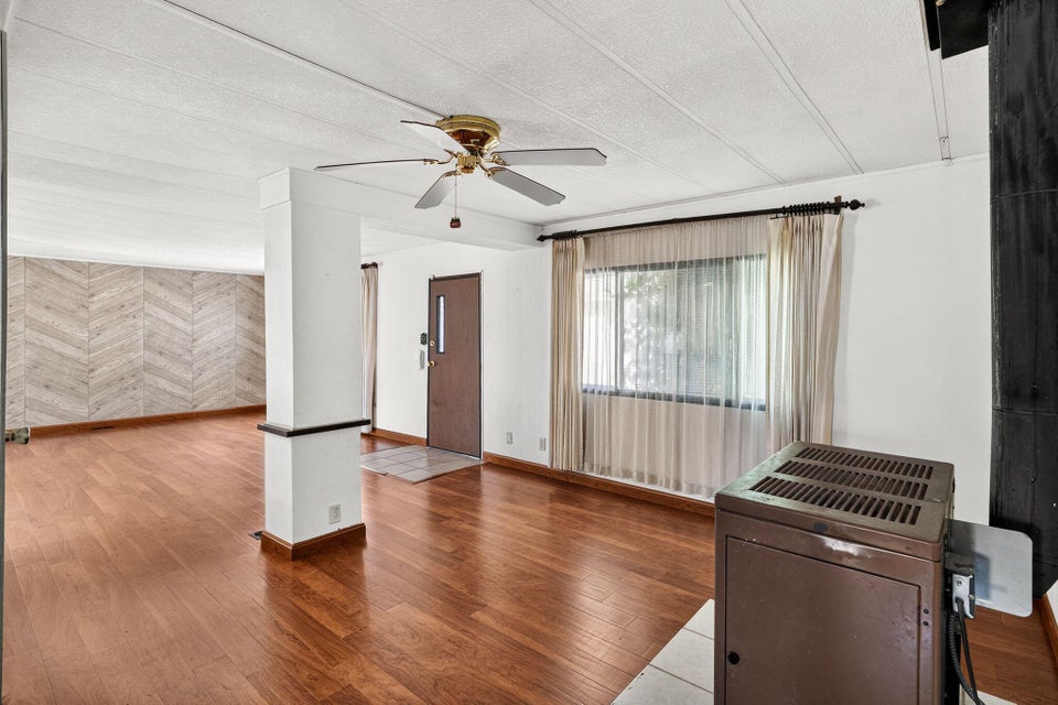 Open-concept living space with wood-finish flooring, a herringbone accent wall, and a ceiling fan