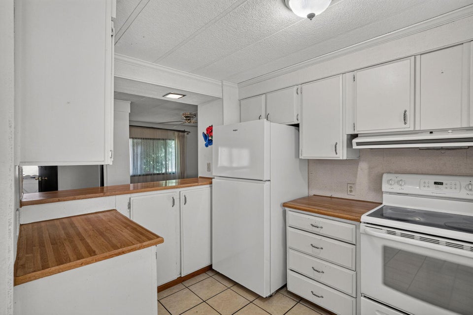 Kitchen featuring white cabinetry, wood-finish countertops, and tile flooring
