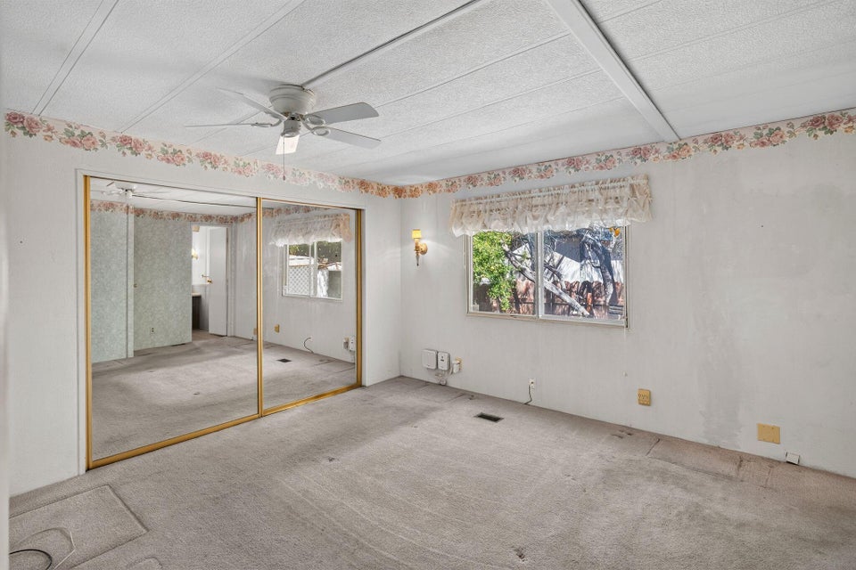 Room featuring a ceiling fan, mirrored closet doors, and a window with a valance