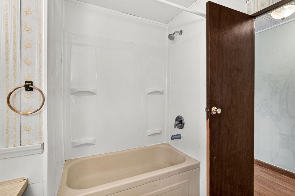 Alcove bathtub with an integrated shower, featuring a white surround and a dark bronze shower fixture