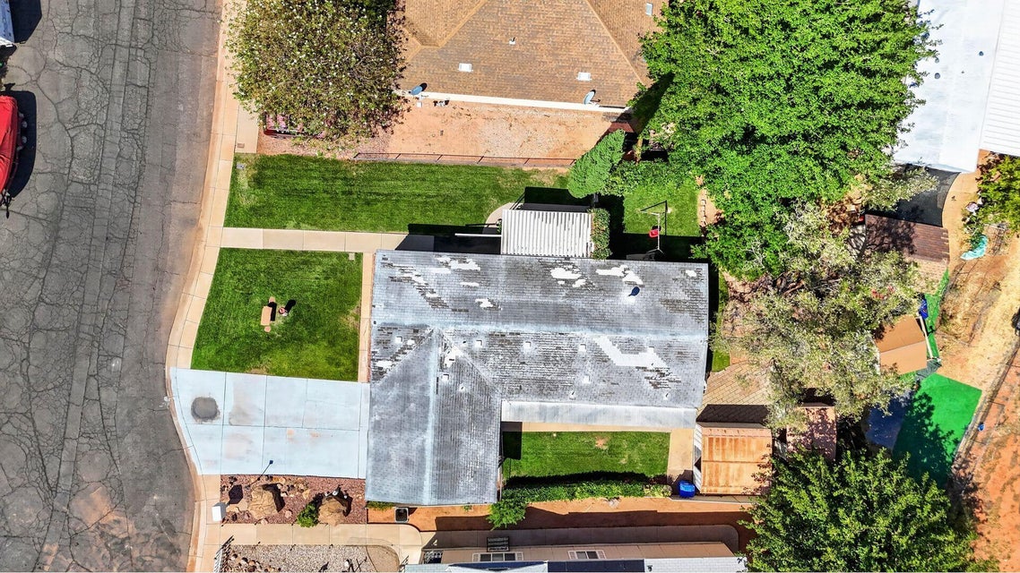 Overhead property view featuring a light-colored roof, a concrete driveway, and front and rear lawn areas