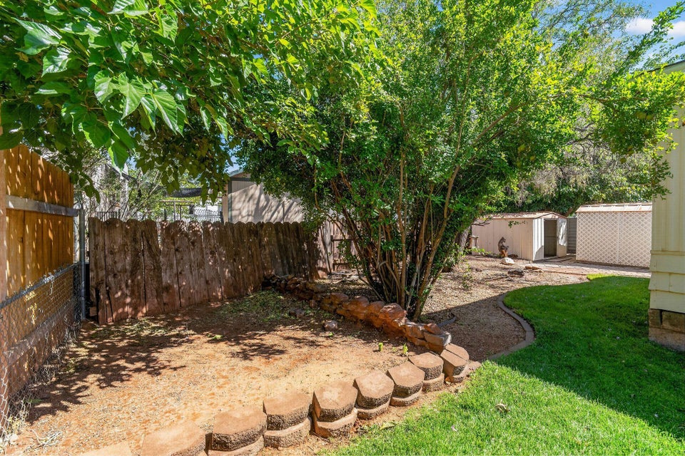 Private outdoor space featuring mature trees, a wood privacy fence, and a decorative block border