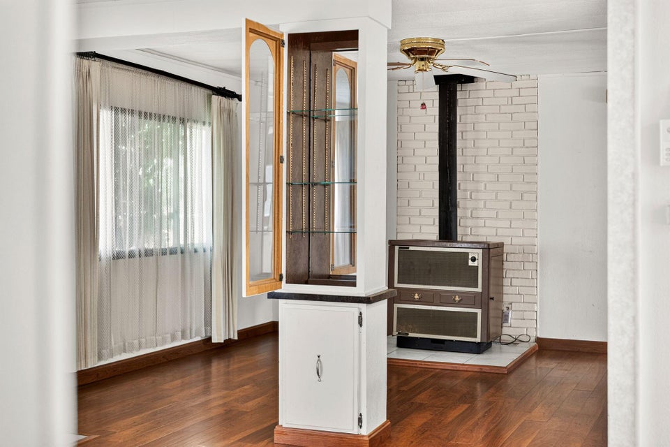 Warm wood-finish flooring complements a built-in display cabinet with glass shelving and a lower storage cabinet