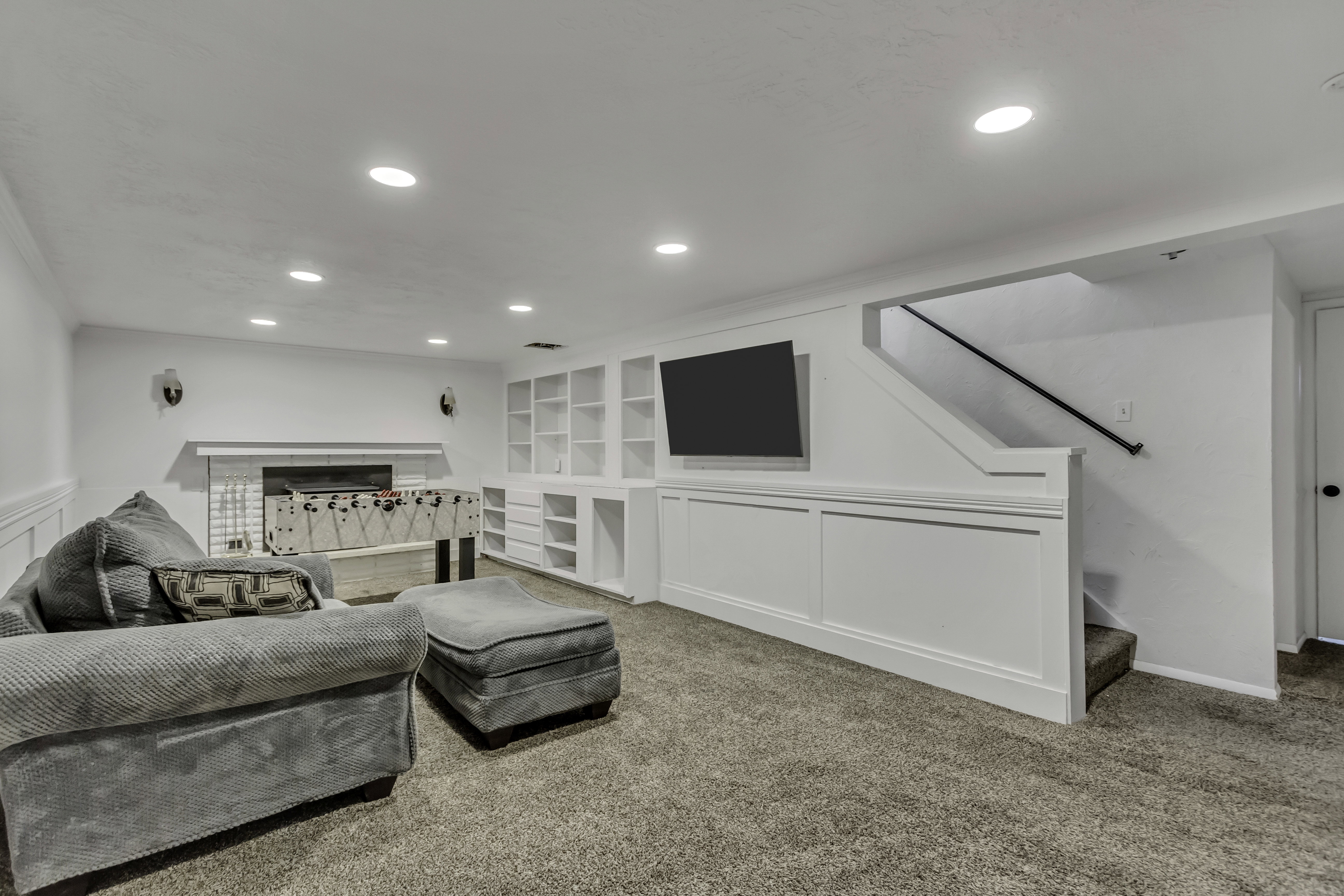 Recreation room featuring recessed lighting, a built-in media center with shelving, a white brick fireplace, and wainscoting details