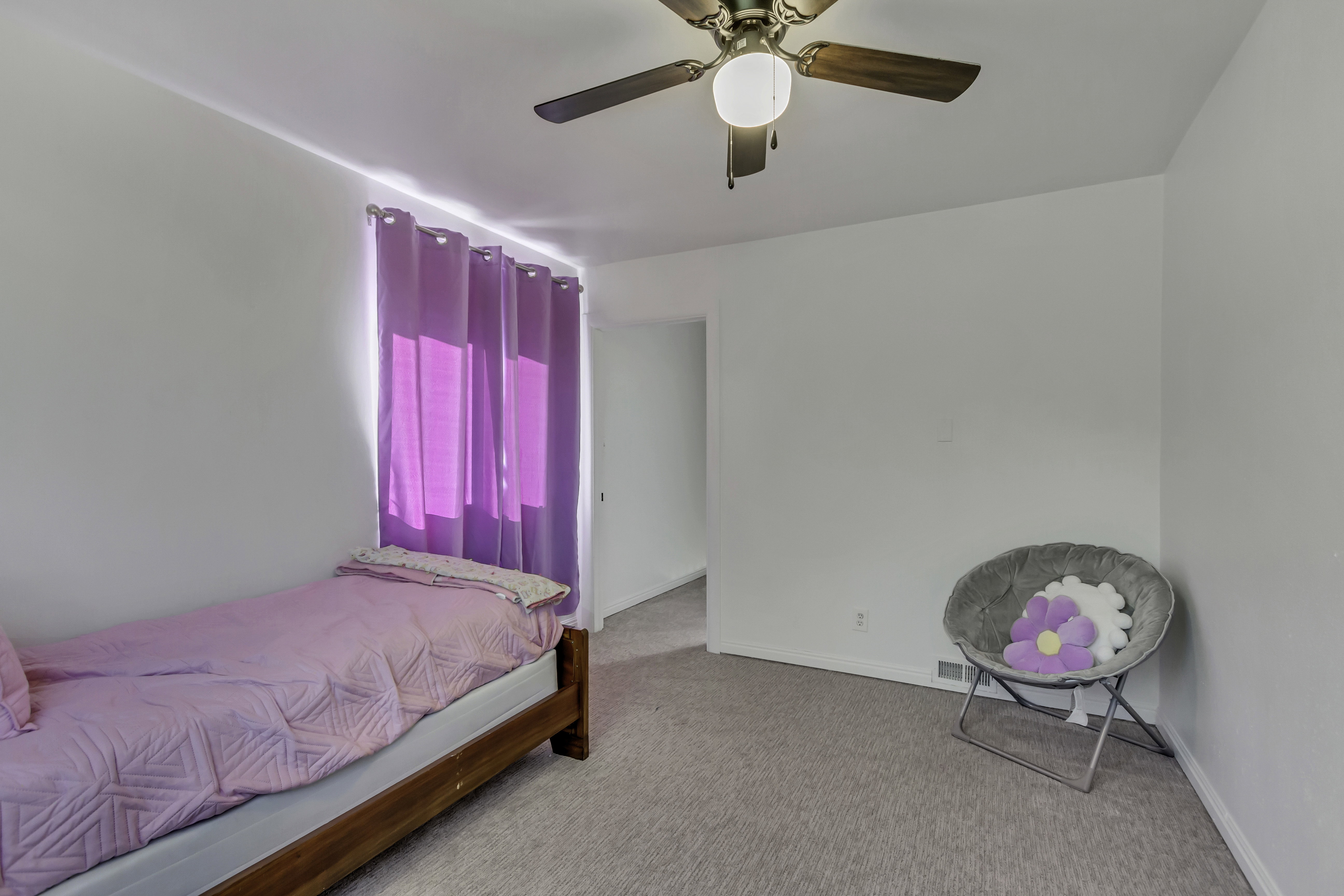 Carpeted room with a ceiling fan light fixture and white walls