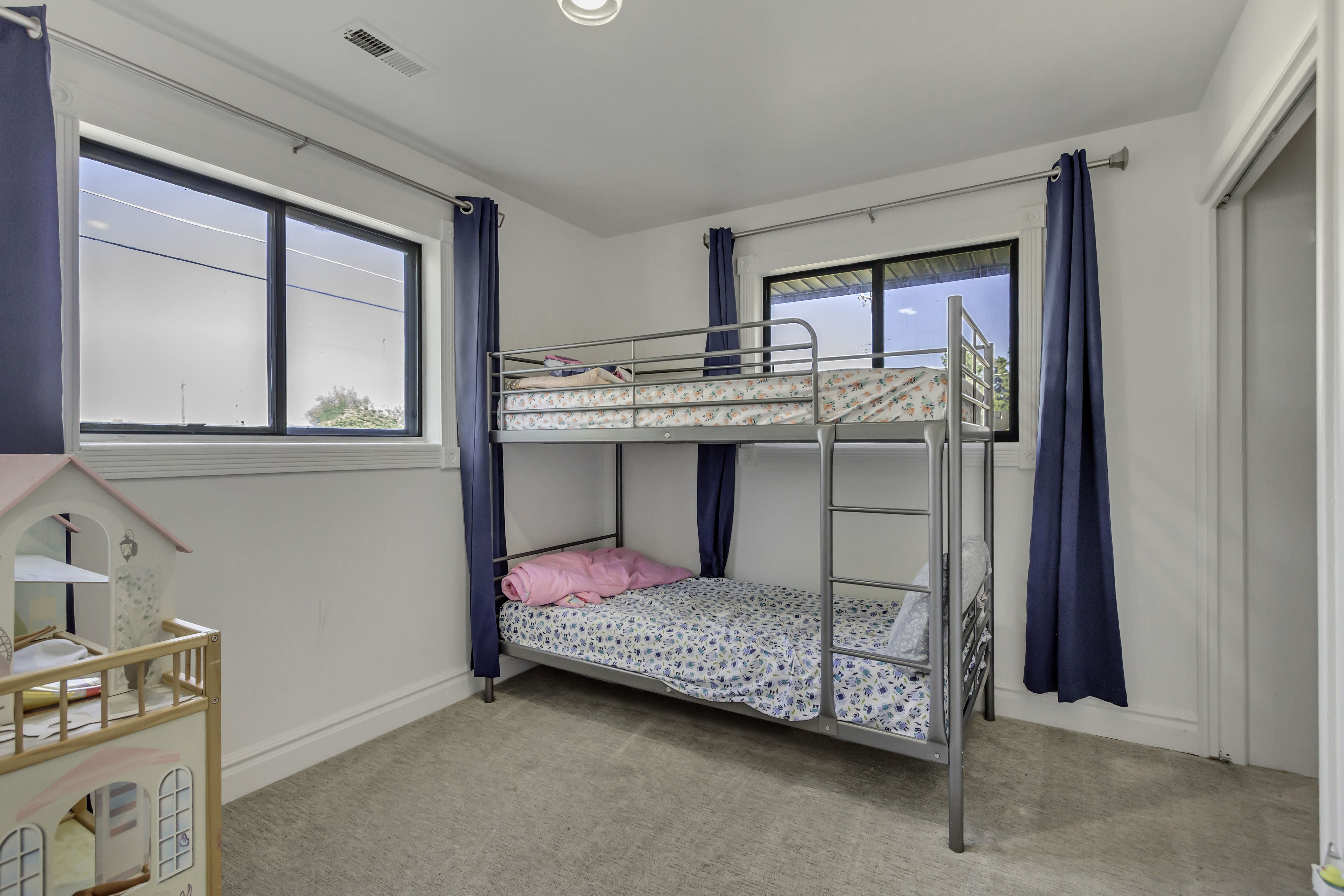 Carpeted room featuring multiple windows with dark frames, white walls, and a built-in closet with a white door