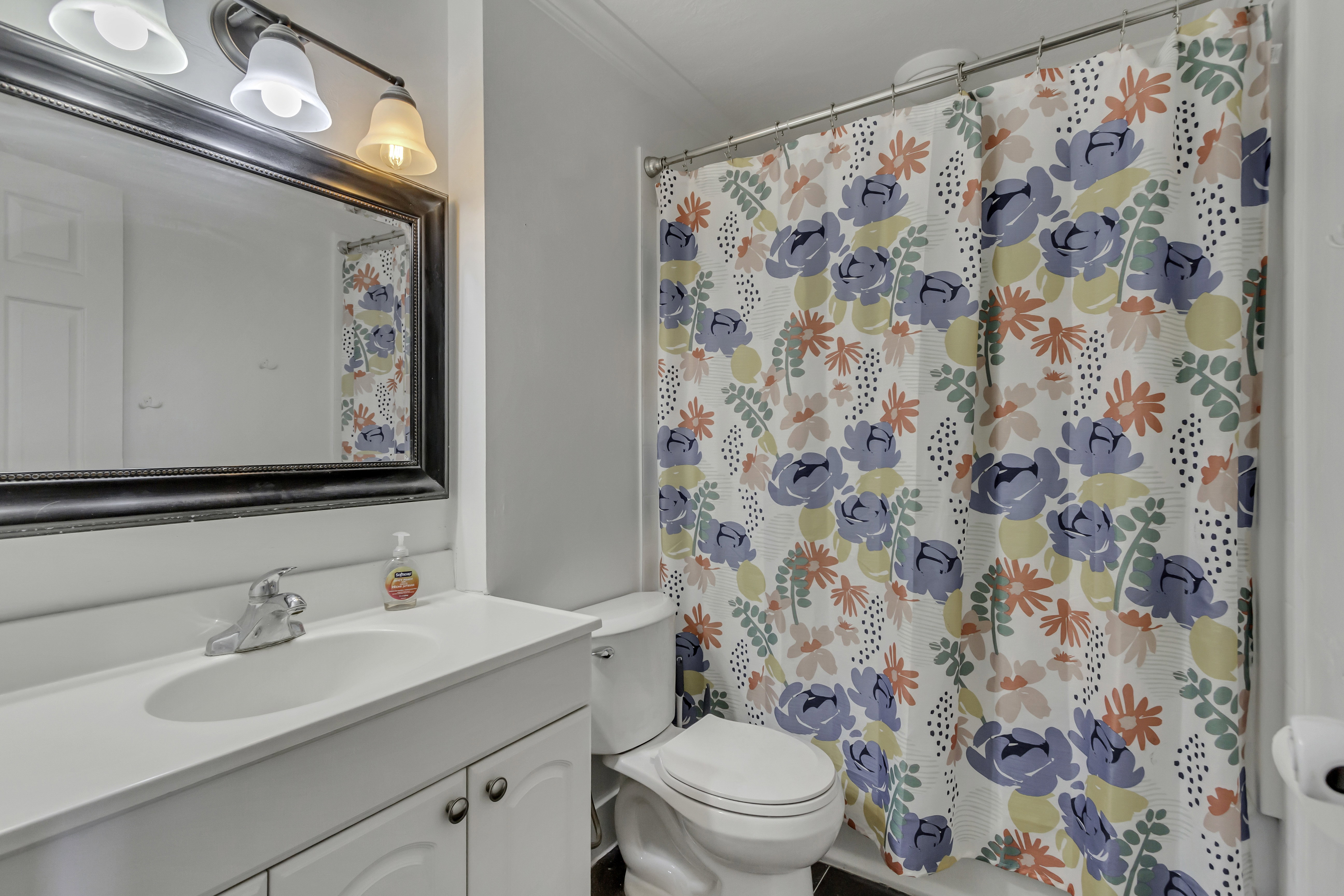 Bathroom featuring a single vanity with an integrated sink, chrome faucet, and white cabinetry