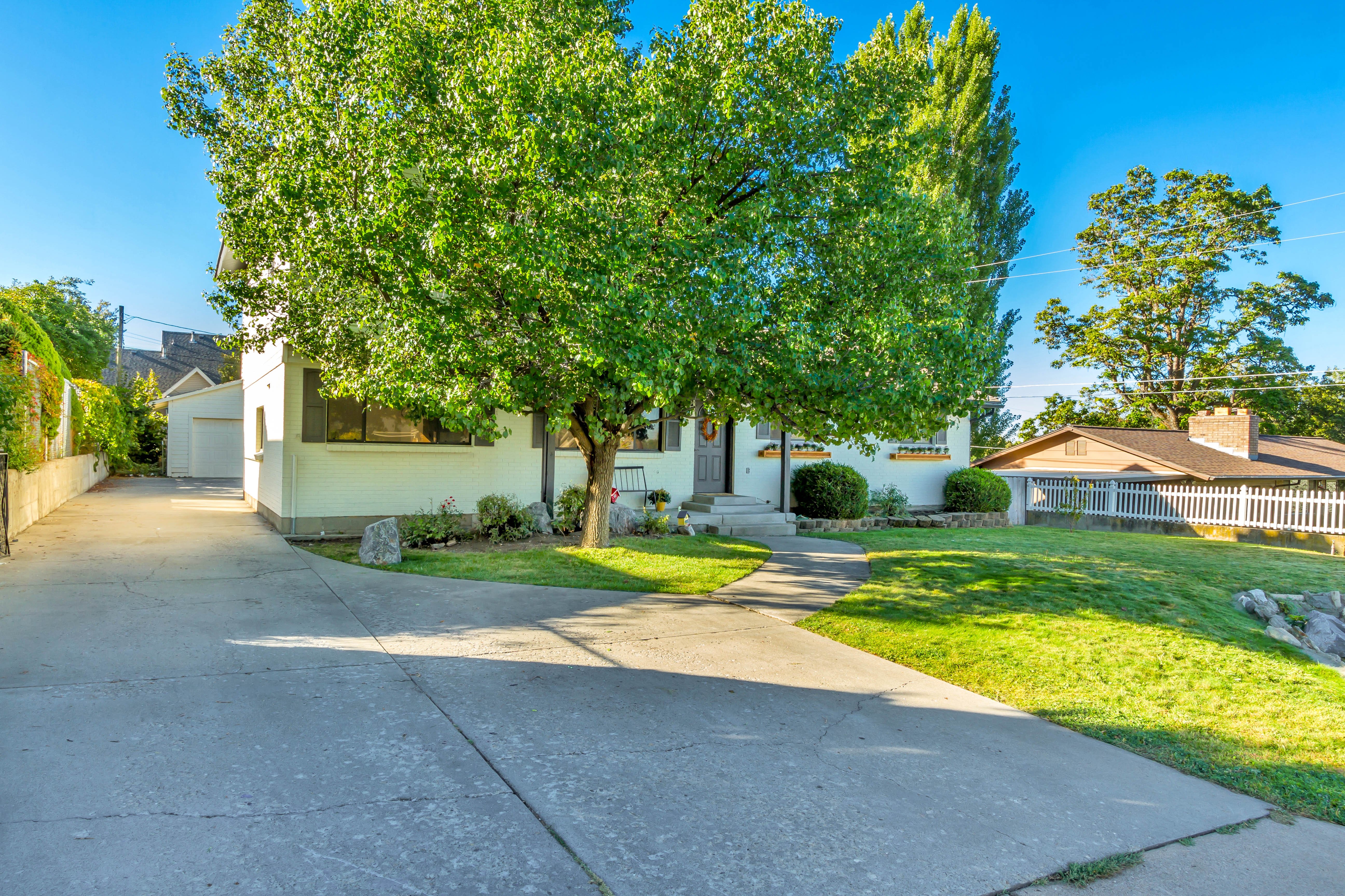 Exterior featuring a concrete driveway, mature landscaping, and a detached garage