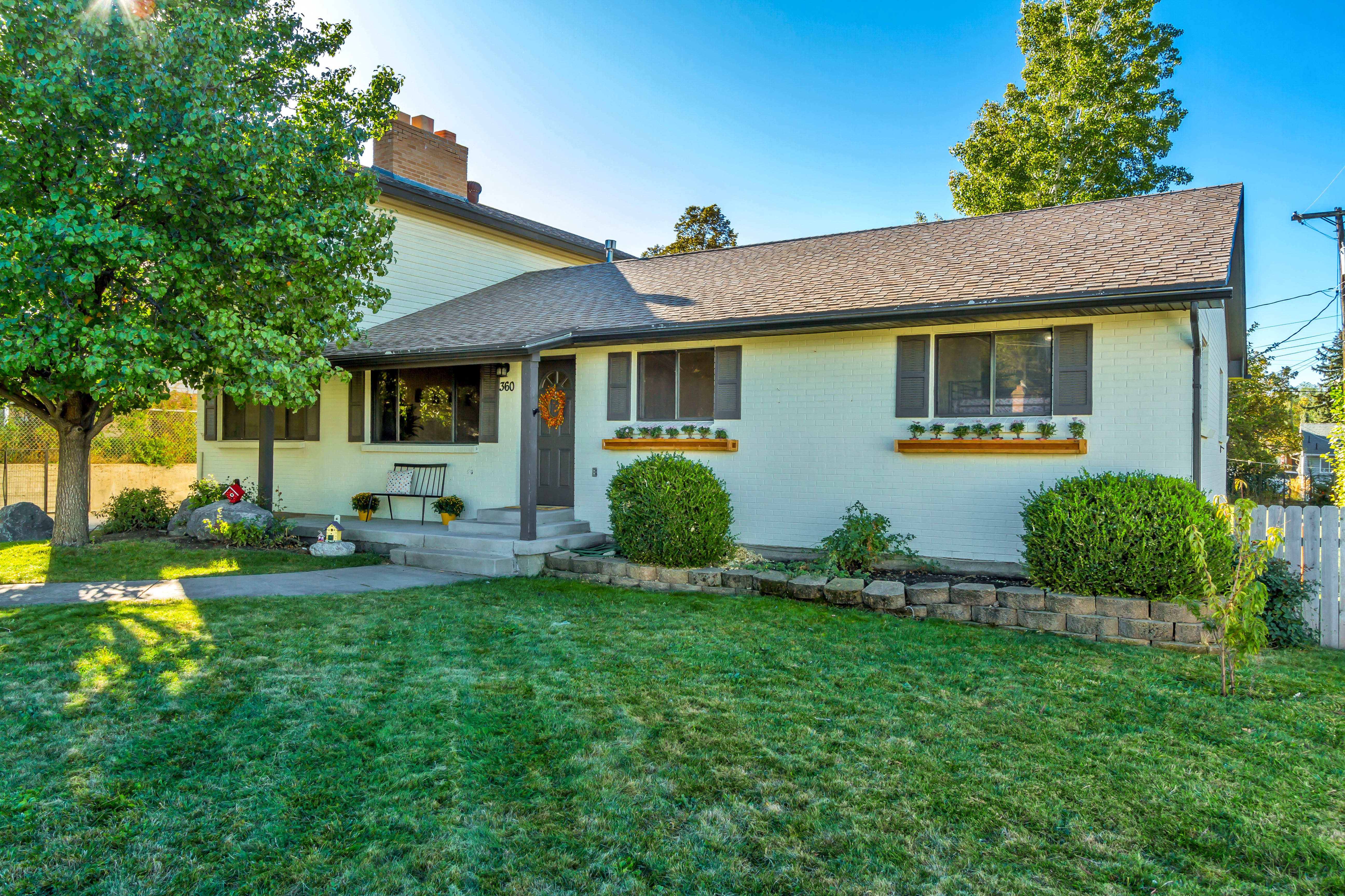 Single-story residence featuring a covered entry, concrete steps, and a white picket fence