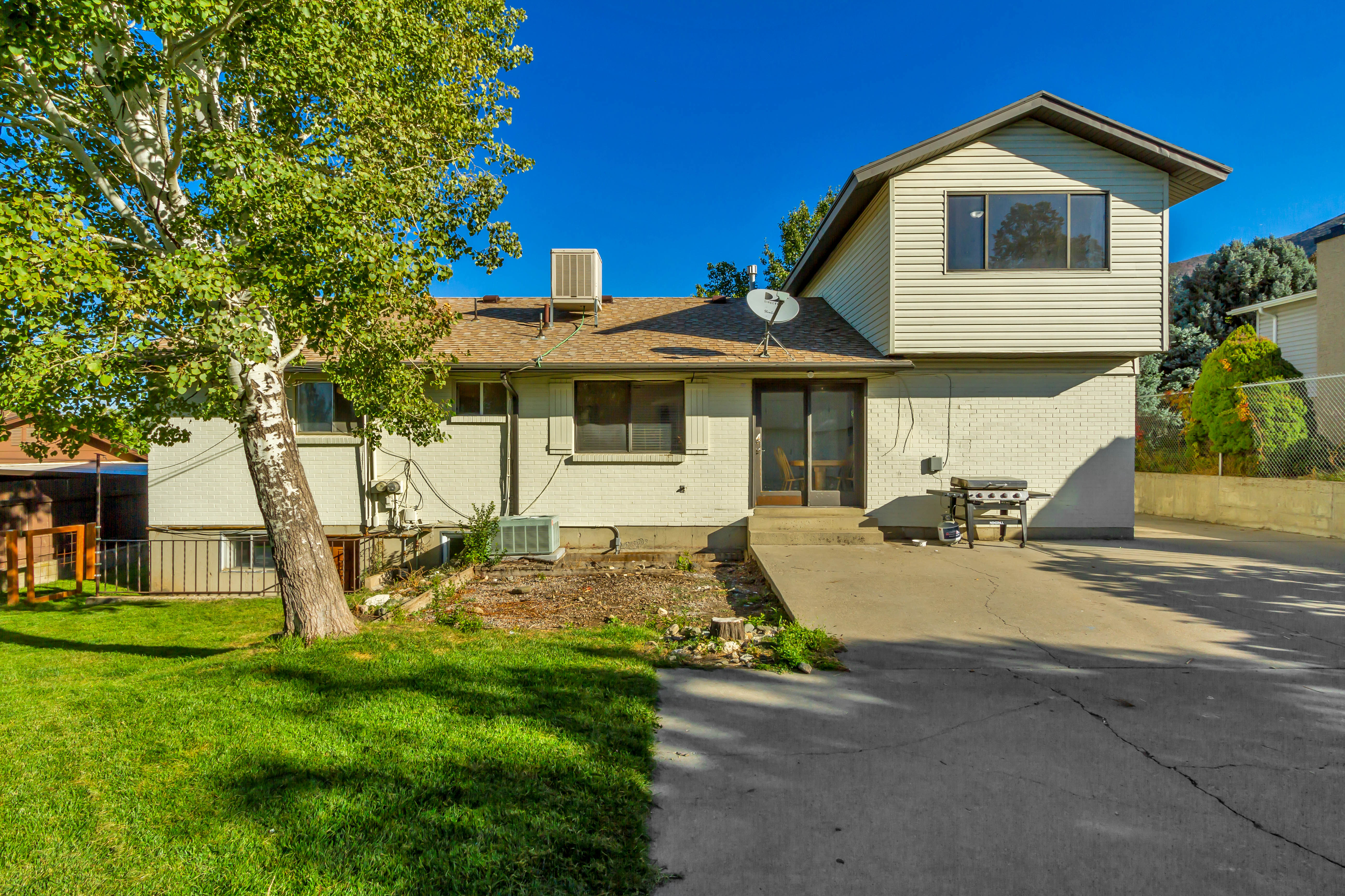 Rear exterior featuring a concrete patio, sliding glass door, and an upper-level extension with siding