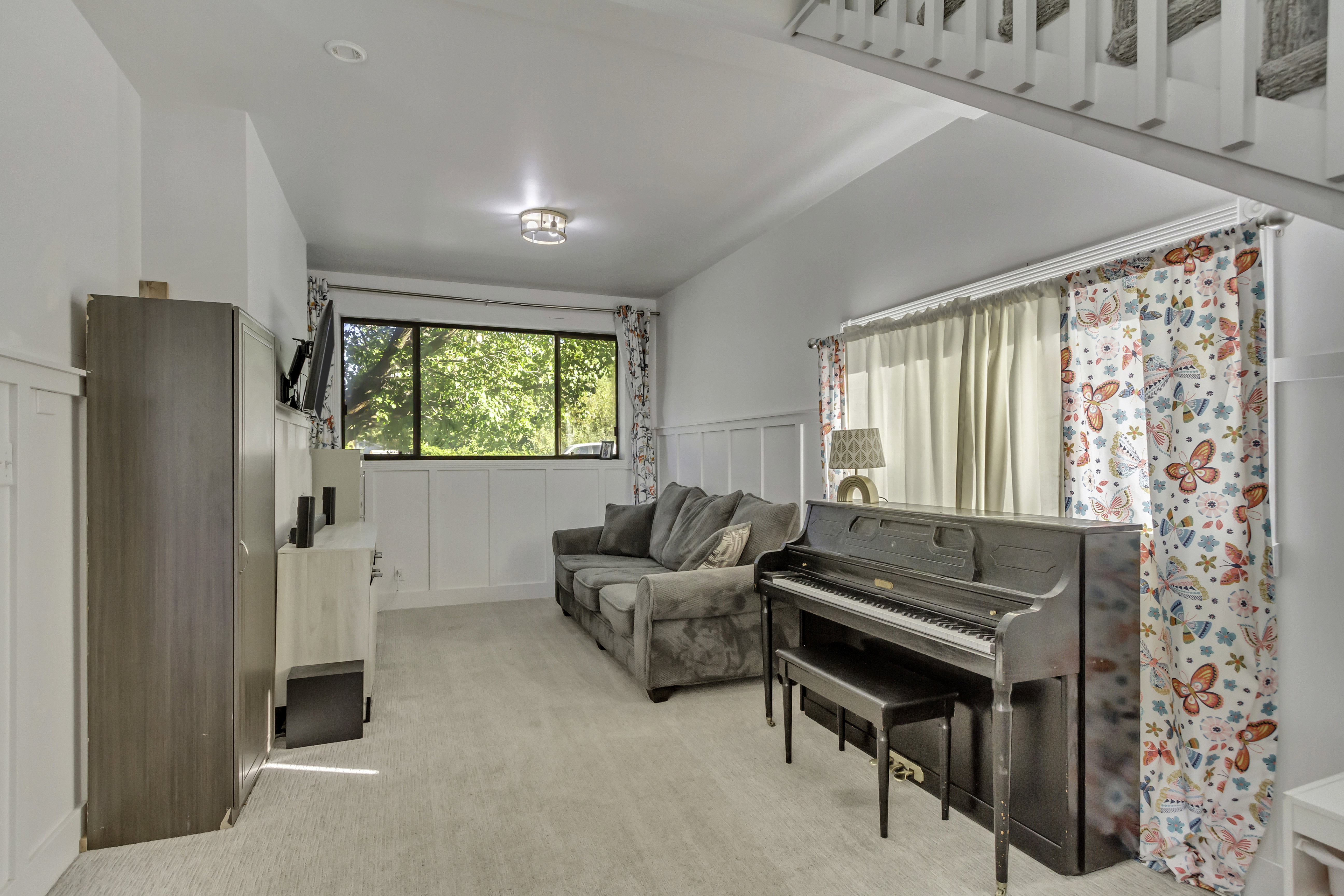 Carpeted living space featuring white wainscoting and a large window