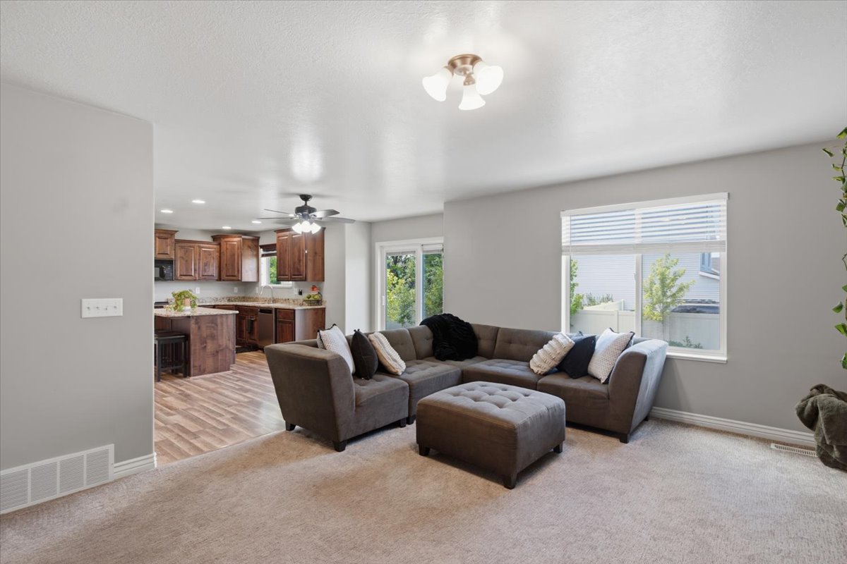 Open-concept living area featuring a neutral color palette, recessed lighting, and a large window providing natural light