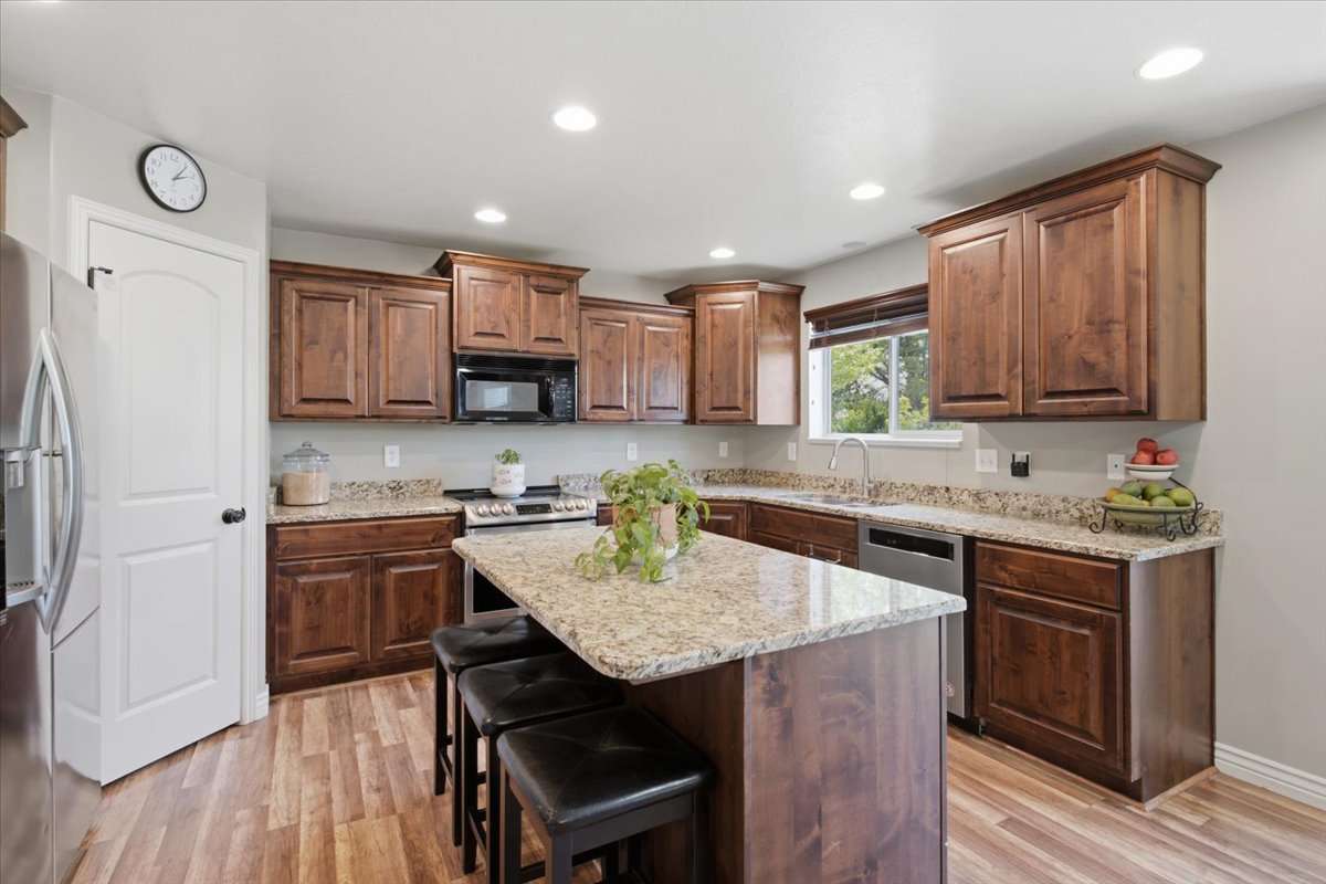 Kitchen featuring wood-finish flooring, recessed lighting, and a window with a valance