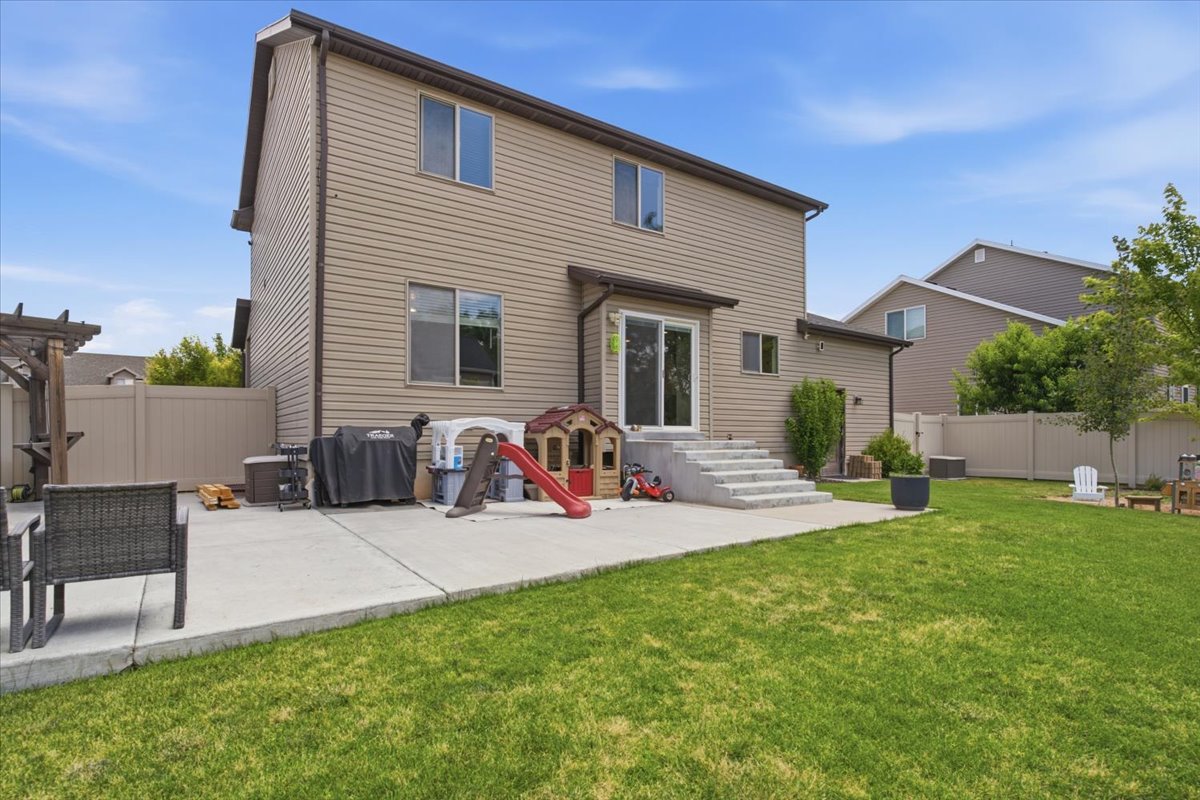 Expansive backyard featuring a manicured lawn, a large concrete patio, and a privacy fence