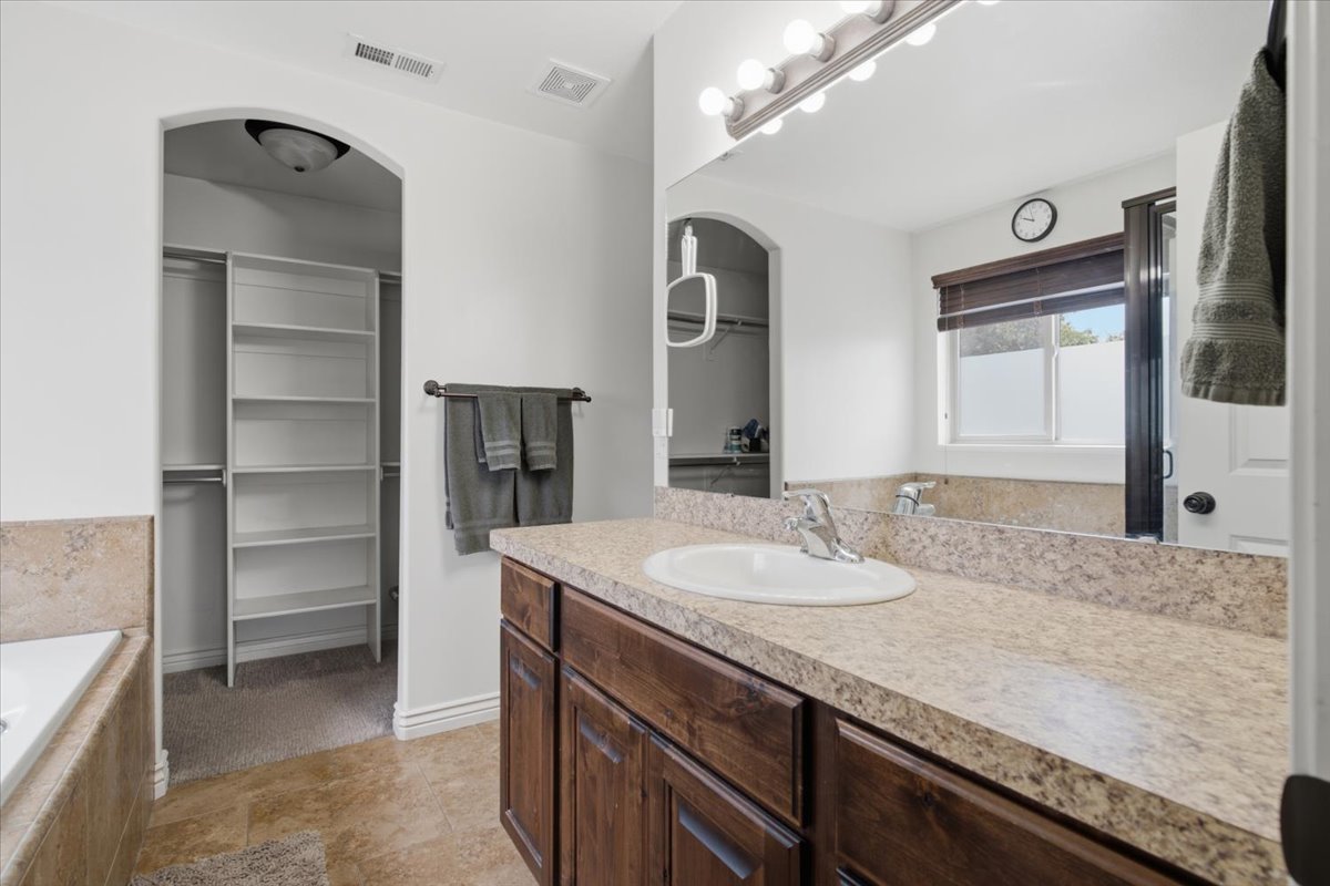 Bathroom vanity featuring a single basin sink, laminate countertop, and wood-finish cabinetry