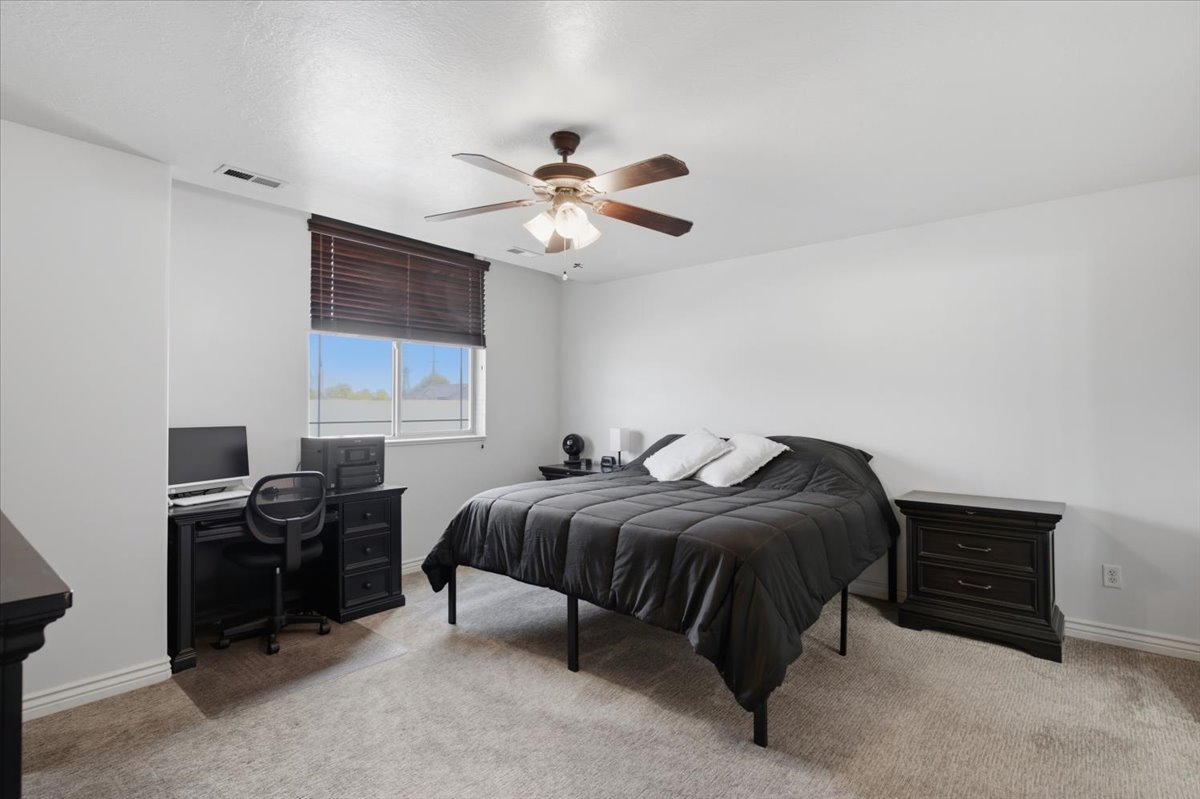 Carpeted room featuring a window with horizontal blinds, a ceiling fan with integrated lighting, and white walls