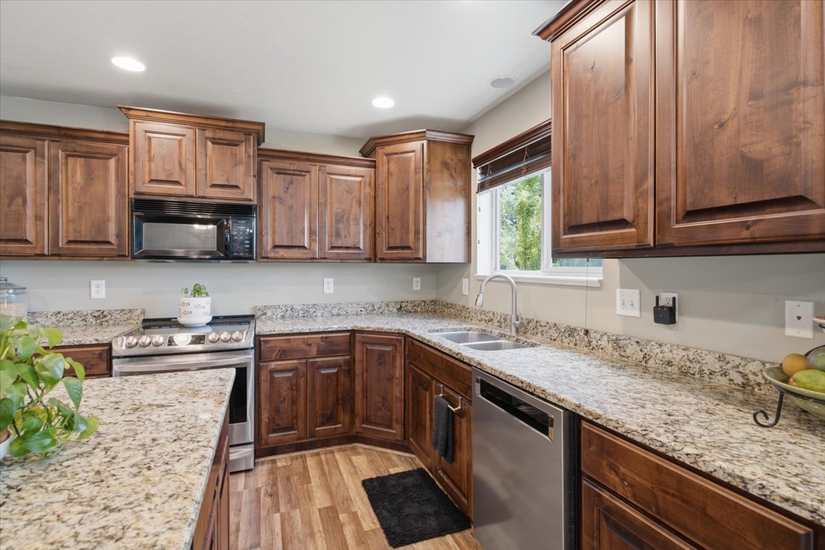 Kitchen featuring dark wood cabinetry, light-toned granite countertops, and wood-finish flooring