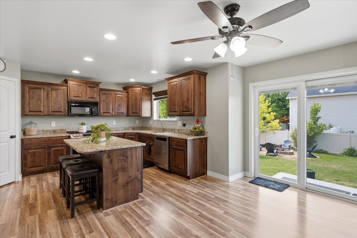 Open-concept kitchen featuring wood-finish flooring, dark wood cabinetry, and a central island with countertop seating