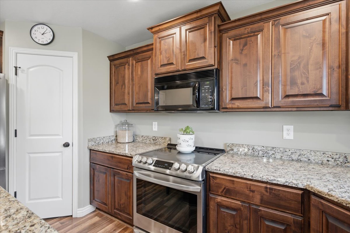 Kitchen featuring rich wood cabinetry, granite countertops, stainless steel range, and an over-the-range microwave