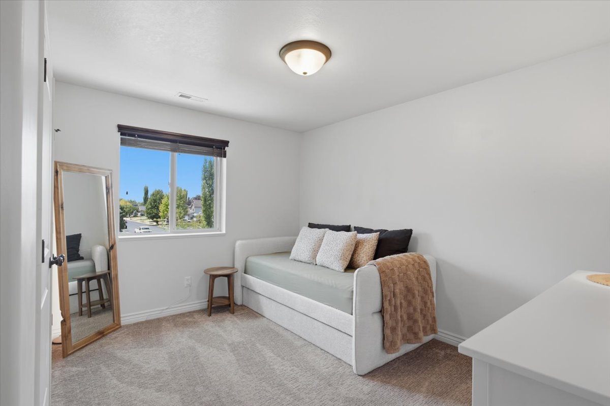 Bright room featuring a large window with dark wood-finish blinds, light-colored carpeting, white walls, and a flush-mount ceiling light fixture