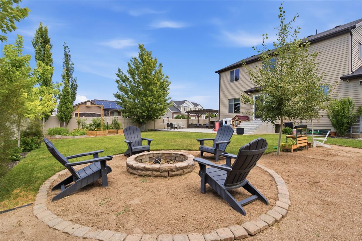 Expansive backyard featuring a stone-lined fire pit area, mature trees, and a spacious lawn