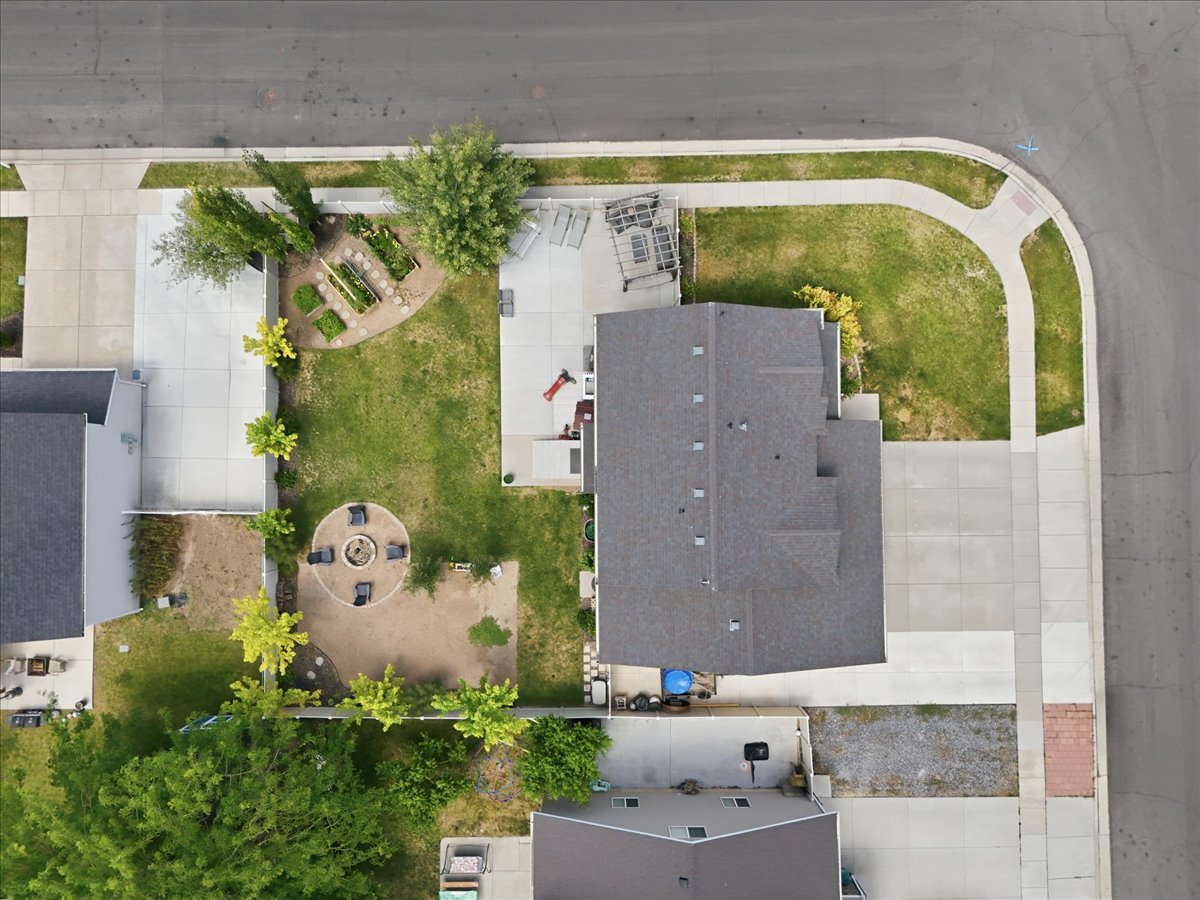 Corner lot property featuring a multi-gable roofline, paved driveway, and established landscaping