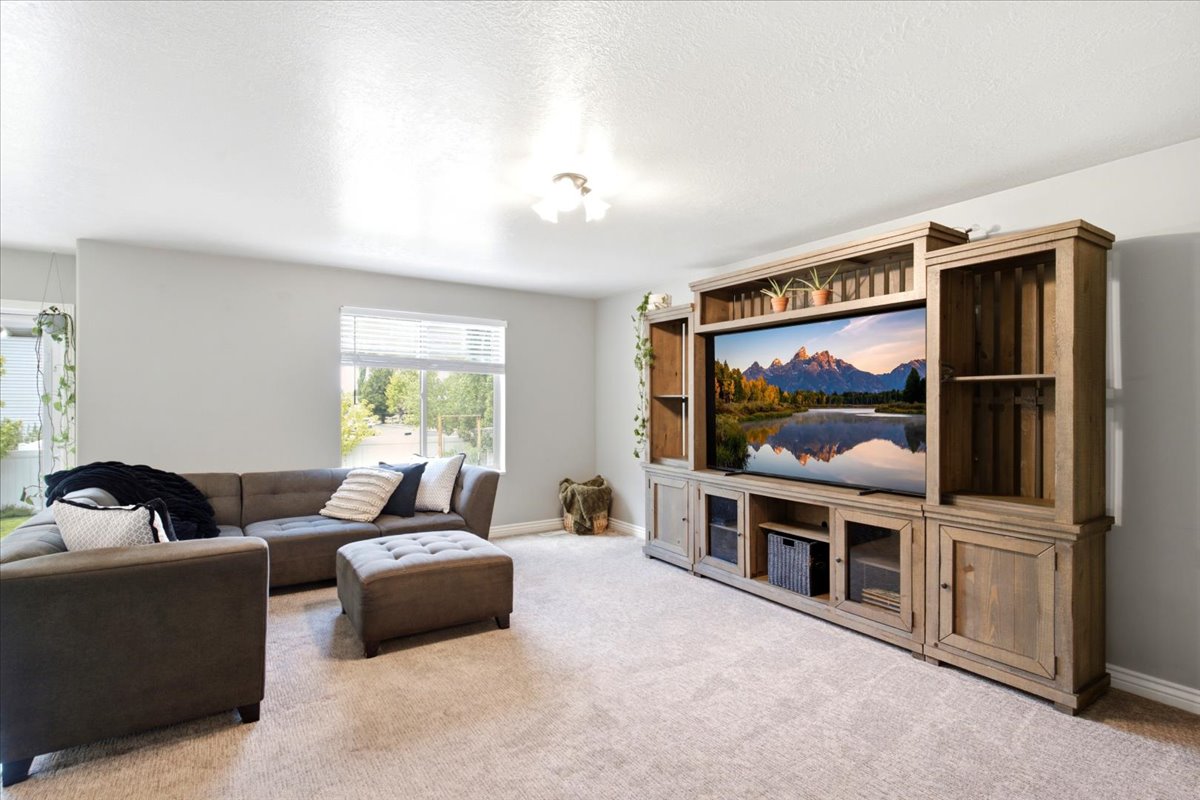 Spacious living area featuring light gray wall paint and neutral carpet