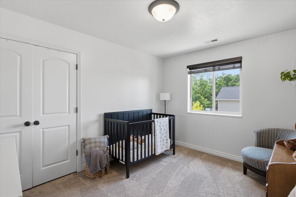 Spacious room featuring neutral carpeting, a large window with roller shades, and a flush mount ceiling light
