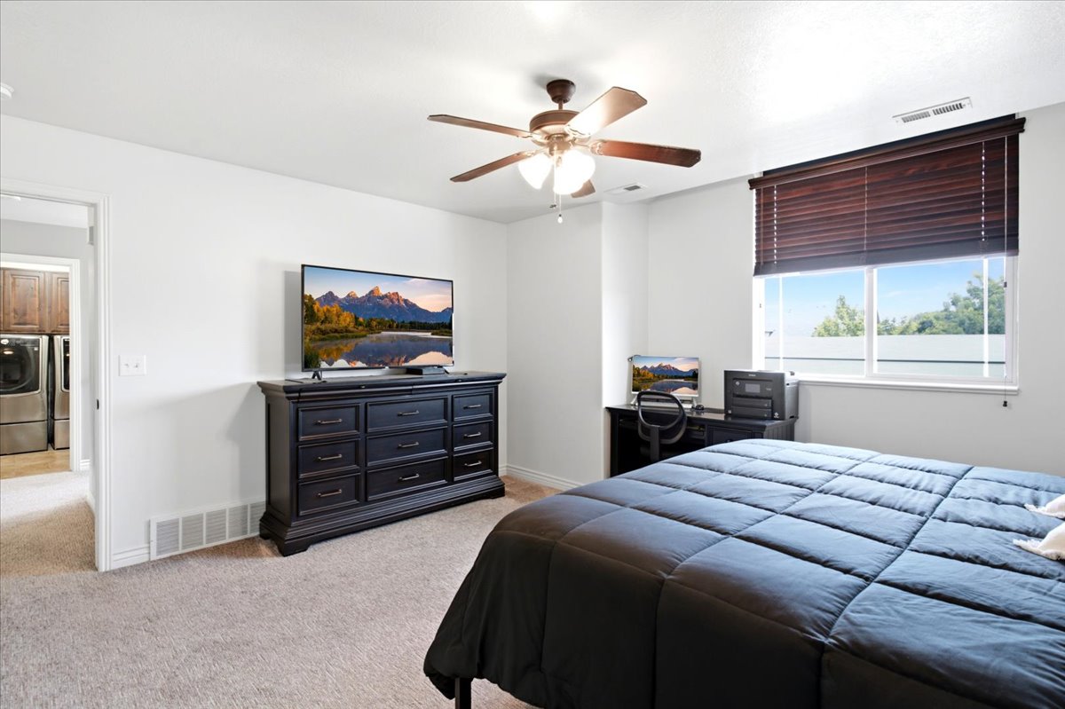 Carpeted room with a ceiling fan, a window featuring horizontal blinds, and a built-in desk