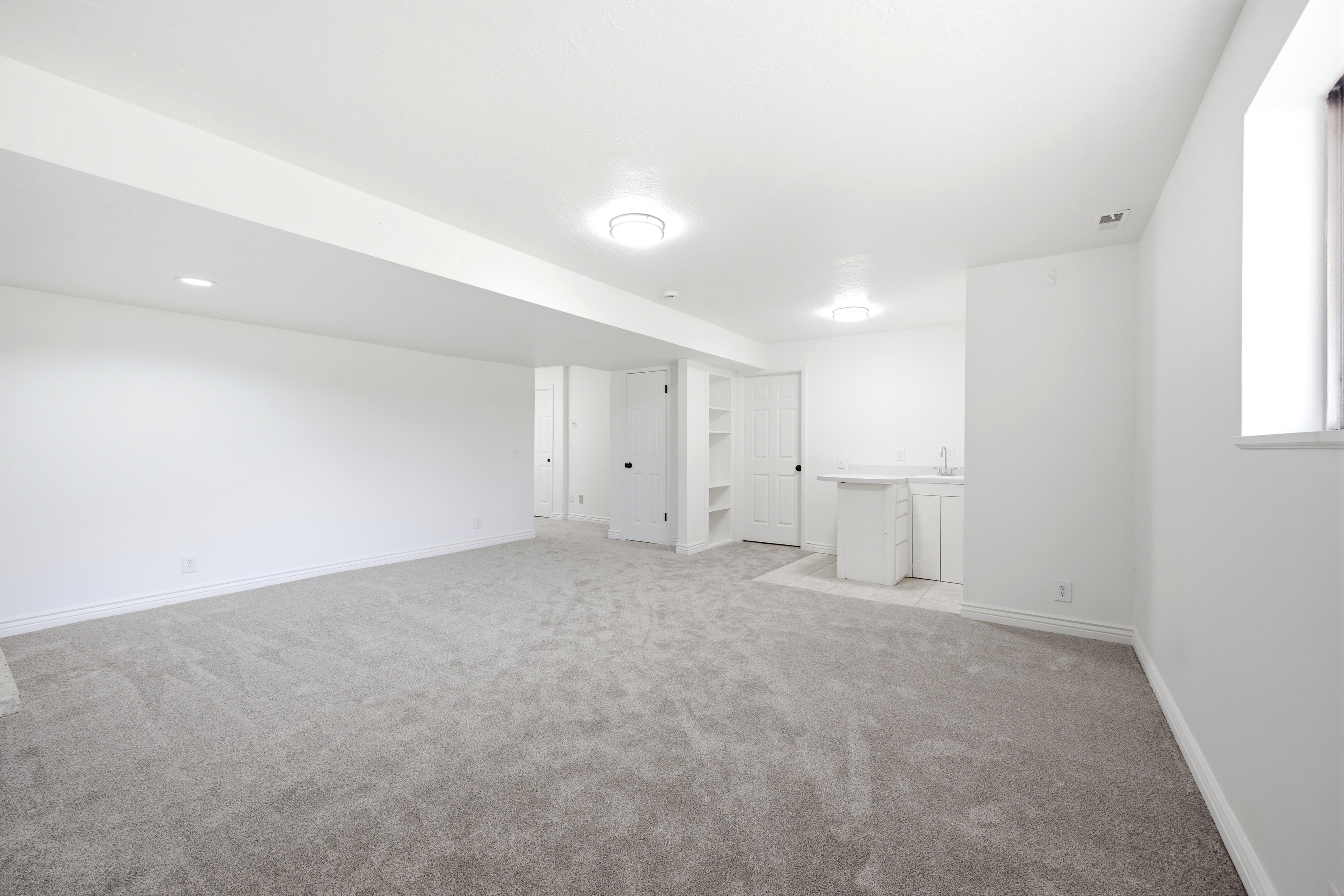 Spacious open-concept room featuring light gray carpeting, white walls, and recessed lighting